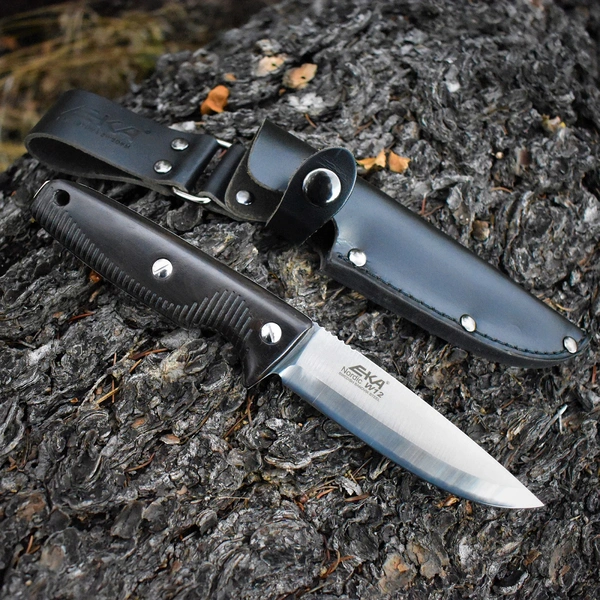 EKA slidkniv med svart grepp och läderslida placerad på trä i skogsmiljö